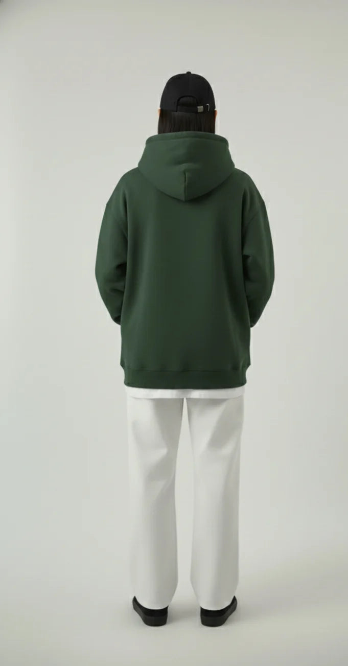 Person wearing a green hoodie and white pants on a white background