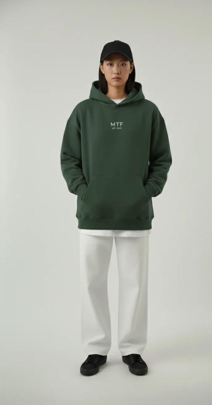 Person wearing a green hoodie with 'MTF' logo on a white background