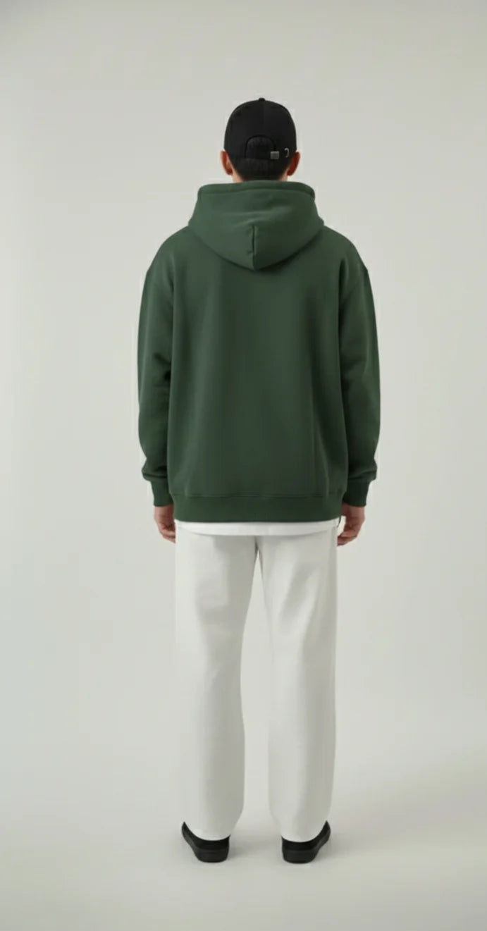 Person wearing a green hoodie and white pants on a plain background